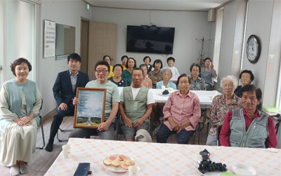 태극기 마을 발랑3리 노인정에서 어르신들과 IWPG 파주지부 회원들이 단체사진을 찍고 있다